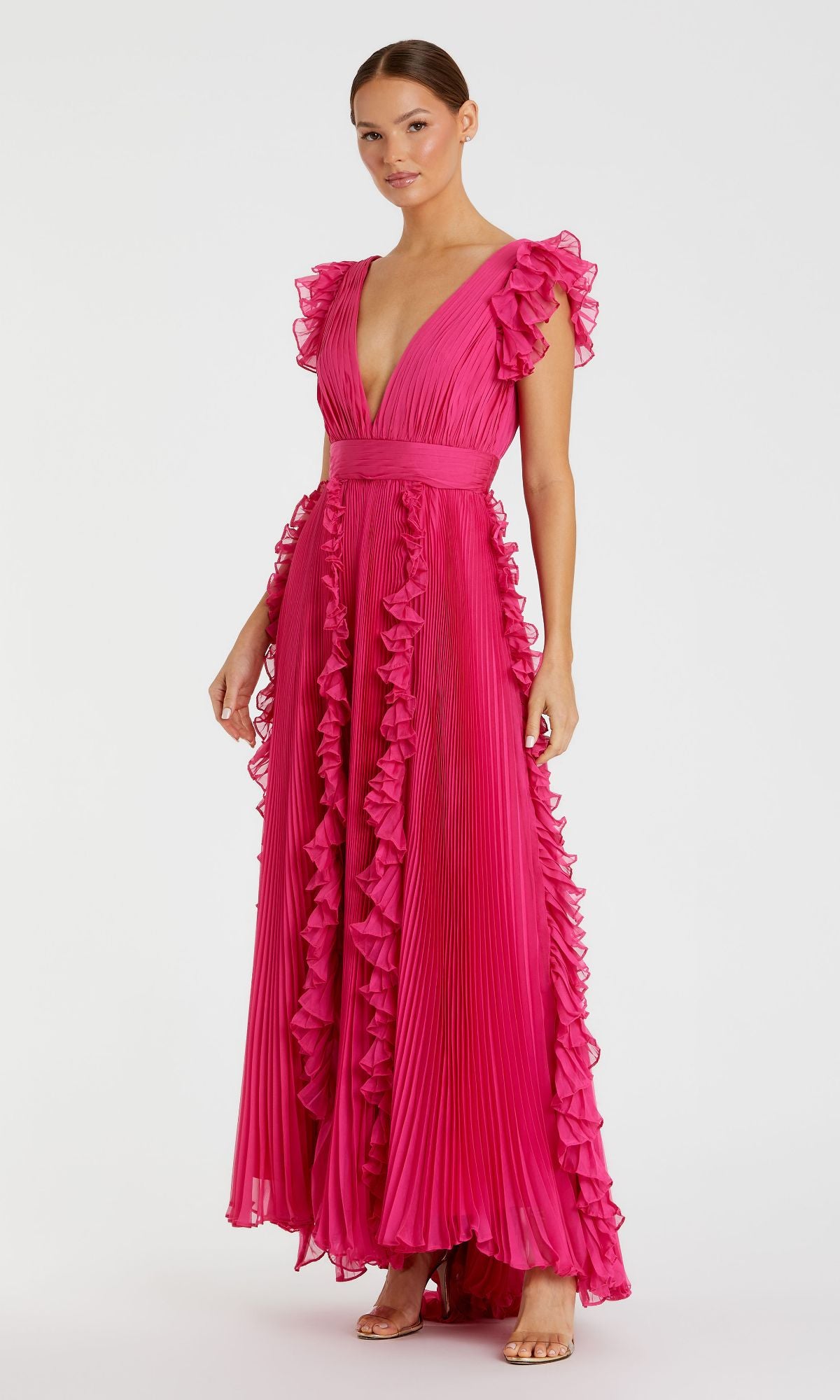 A woman models the Mac Duggal Ruffle-Sleeve Long Formal Dress 49539 in hot pink, featuring a deep V-neckline and pleated fabric, paired with open-toe heels against a plain white background.